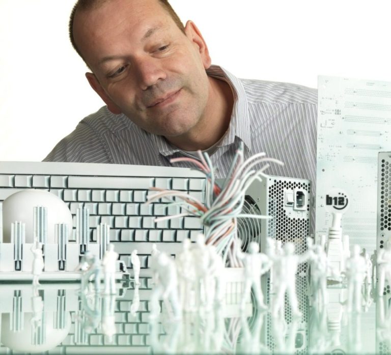 Managed Services CEO René Carstanjen beobachtet die Miniaturfiguren und elektronische Geräte, und überprüft, ob diese gut funktionieren