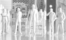 IT-Sicherheit Eine monochrome Darstellung von Miniaturgebäuden und Kabeln auf einem Tisch.
