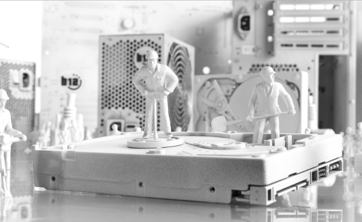 IT-Sicherheit Eine monochrome Darstellung von Miniaturgebäuden und Kabeln auf einem Tisch.