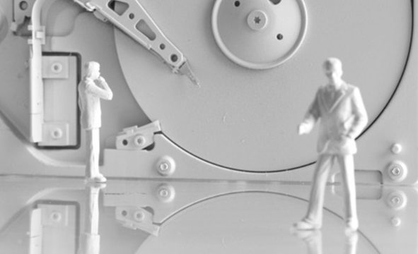 IT-Sicherheit Eine monochrome Darstellung von Miniaturgebäuden und Kabeln auf einem Tisch.