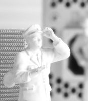 Zukunftssicherheit Weißer Figurenmensch in Uniform, Hand an der Stirn, schaut aufmerksam.
