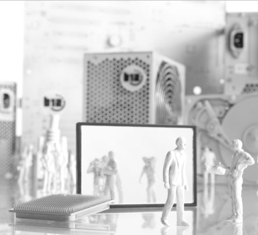 Konfiguration Miniaturfiguren in einer technischen Umgebung, mit einem Tablet und einem Buch im Vordergrund.